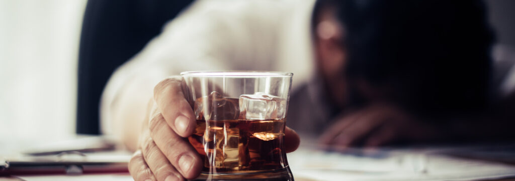 Person passed out at desk from binge drinking alcohol.